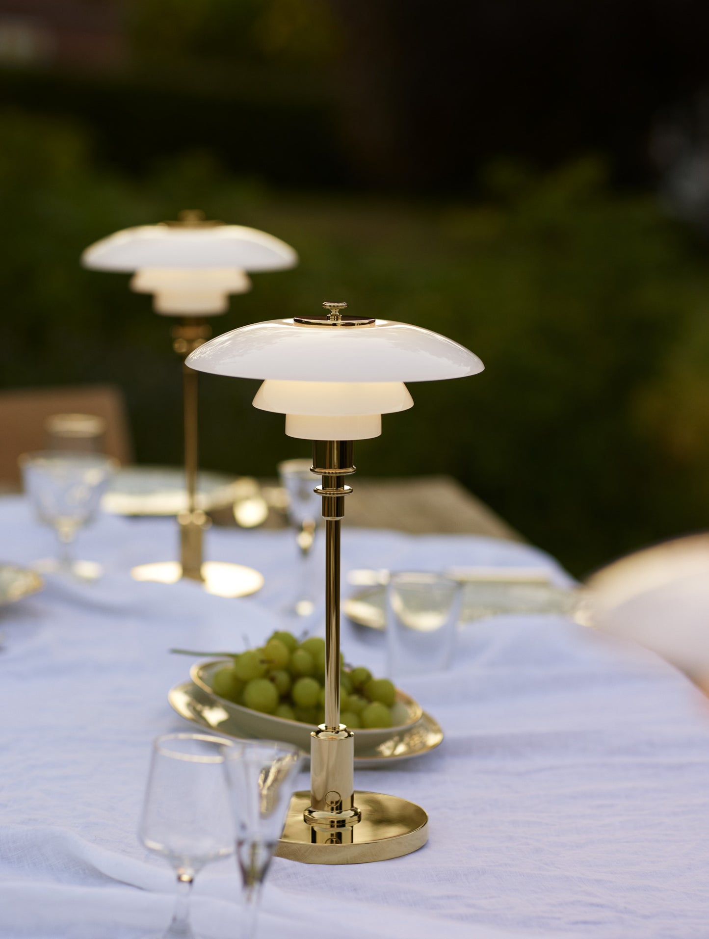 Louis poulsen ph 2/1 bordlampe i brass som står på et bord udenfor