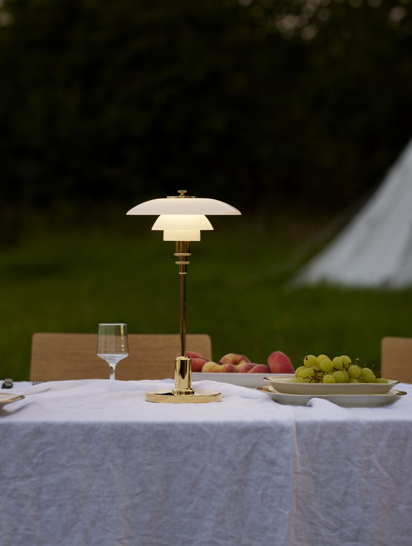 Louis poulsen ph 2/1 bordlampe i brass som står på et bord udenfor tændt