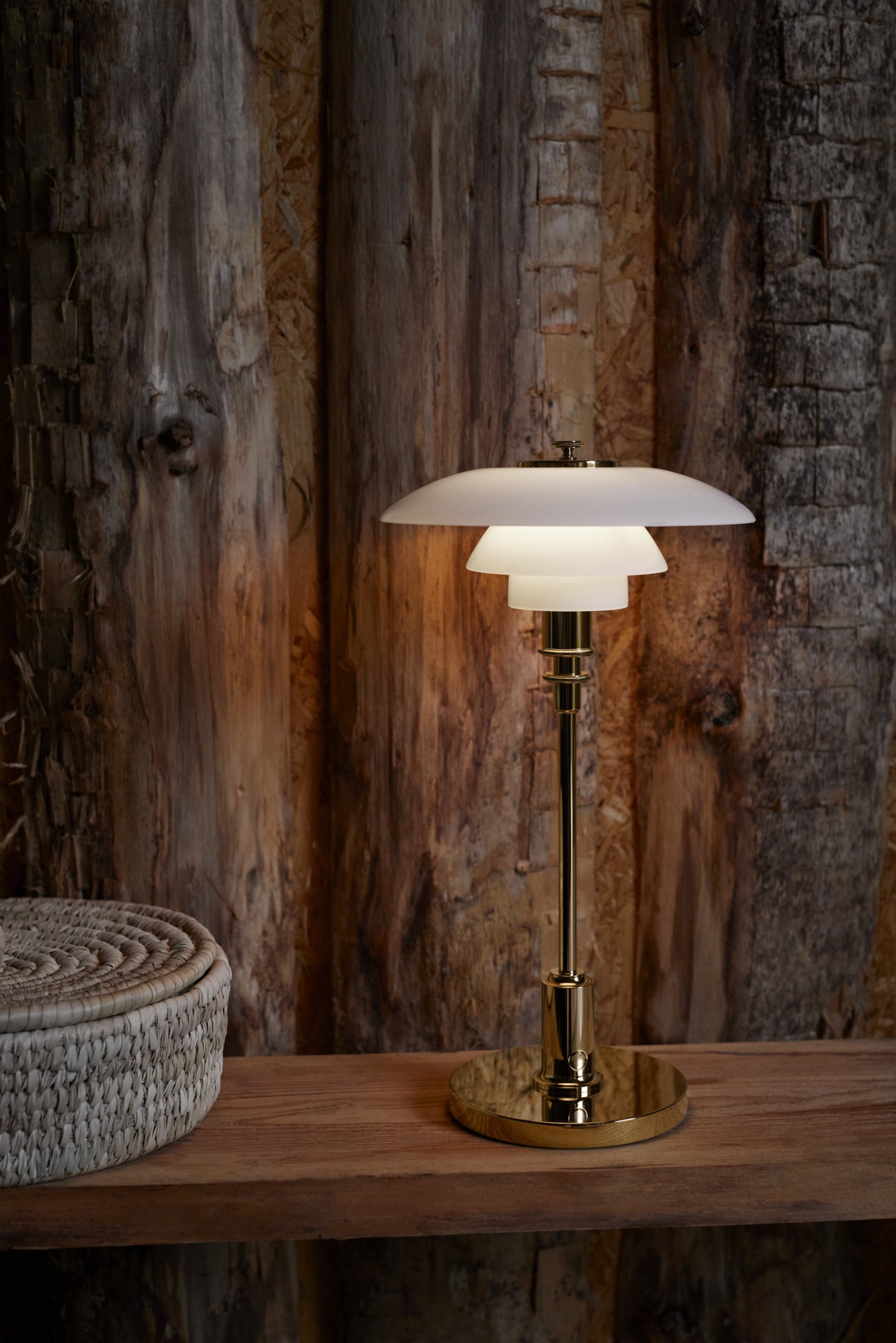 Louis poulsen ph 2/1 bordlampe i brass som står på et træ bønk med træ baggrund