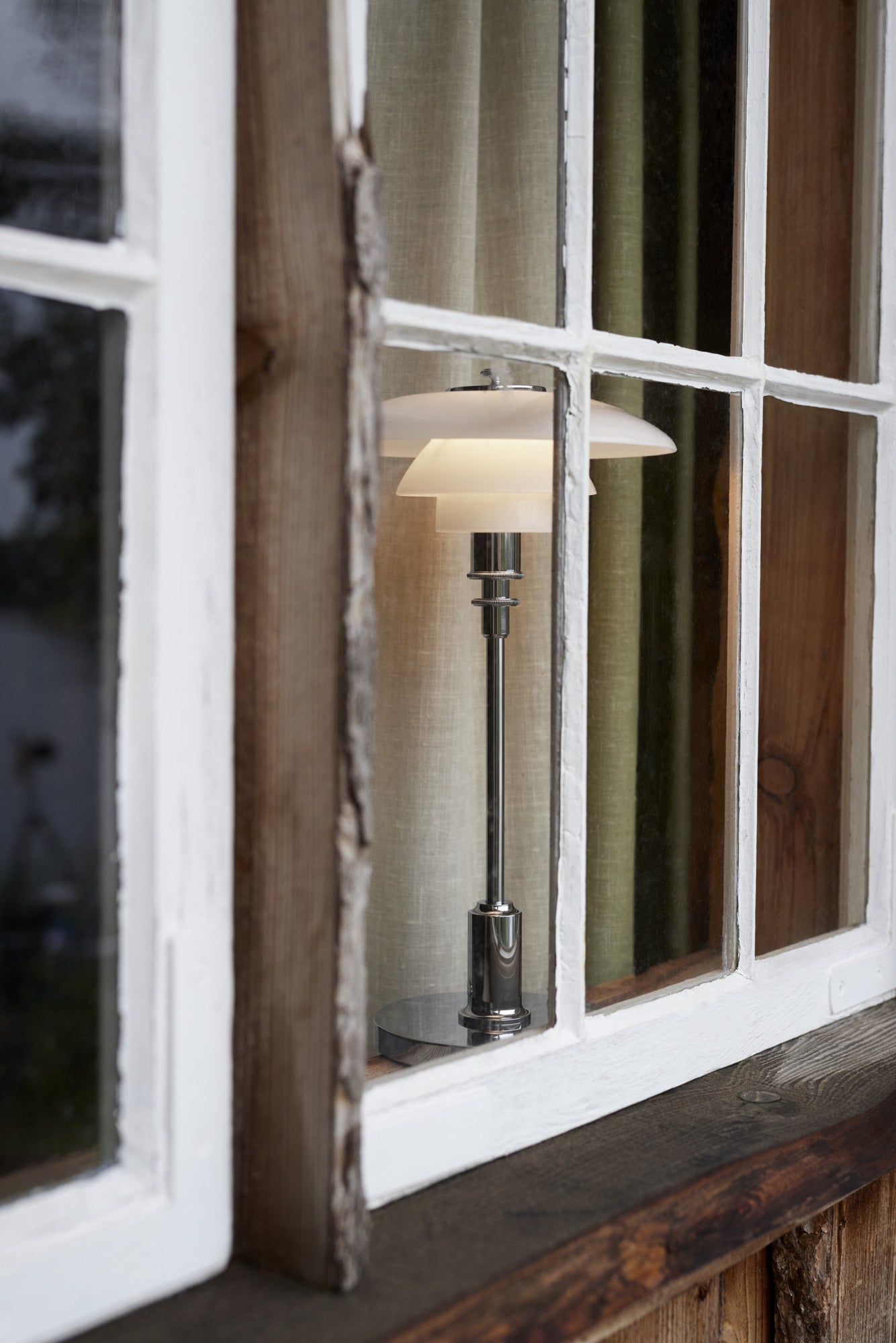 Et Louis poulsen ph 2/1 bordlampe i brass nærbillede i et vindue