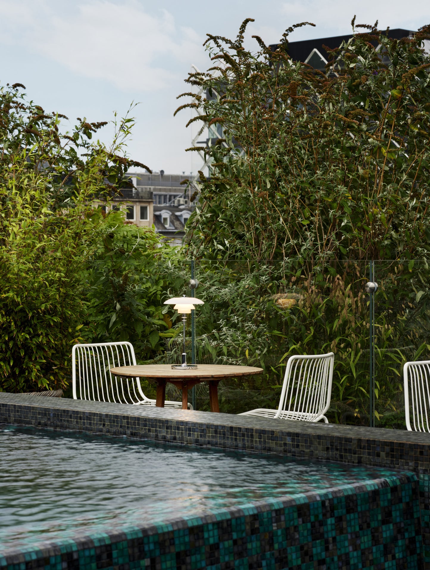 En Louis poulsen ph 2/1 bordlampe i brass som står på et bord ved en pool